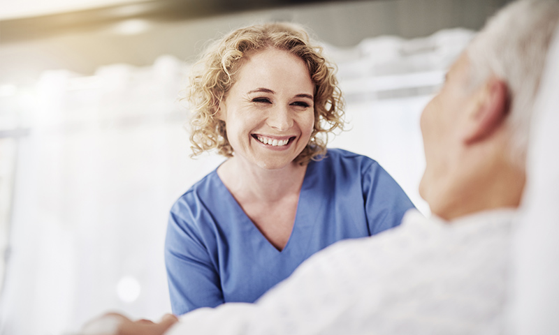 Lächelnde Pflegefachfrau im Gespräch mit Patienten